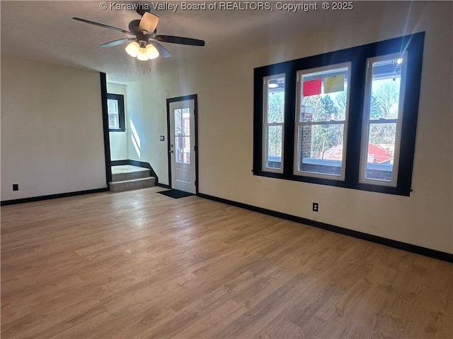 spare room with a ceiling fan, stairway, baseboards, and wood finished floors