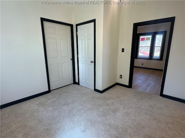 unfurnished bedroom featuring light carpet and baseboards