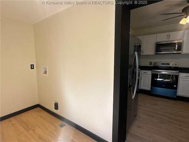 kitchen featuring baseboards, dark countertops, ceiling fan, appliances with stainless steel finishes, and wood finished floors