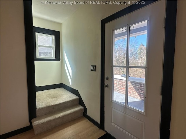 entryway with light wood finished floors, stairway, and baseboards