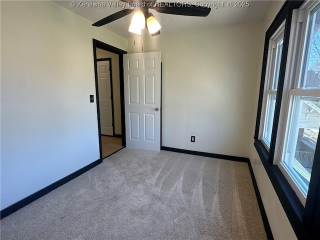 empty room featuring carpet, baseboards, ceiling fan, and a textured ceiling