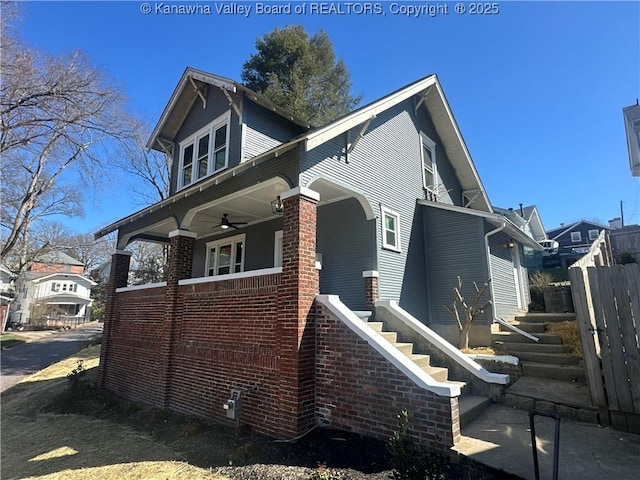 view of home's exterior with ceiling fan, stairs, fence, and brick siding