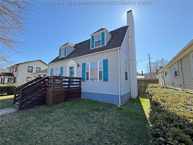 back of house featuring roof with shingles, a chimney, a lawn, fence, and a deck