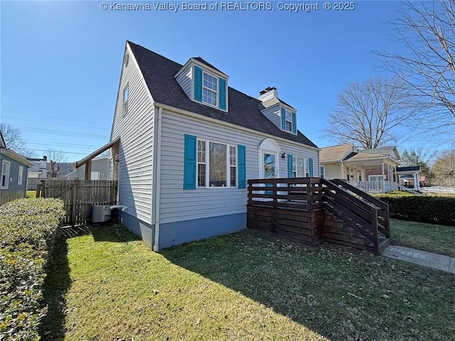 view of front of house with a shingled roof, fence, a deck, a front lawn, and central AC