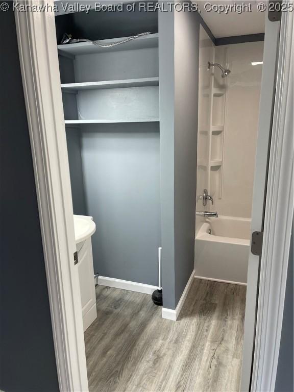 full bath with shower / bath combination, wood finished floors, vanity, and baseboards