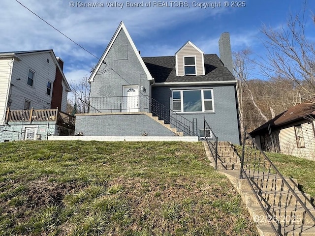 view of front of property with brick siding, fence, a chimney, and a front lawn