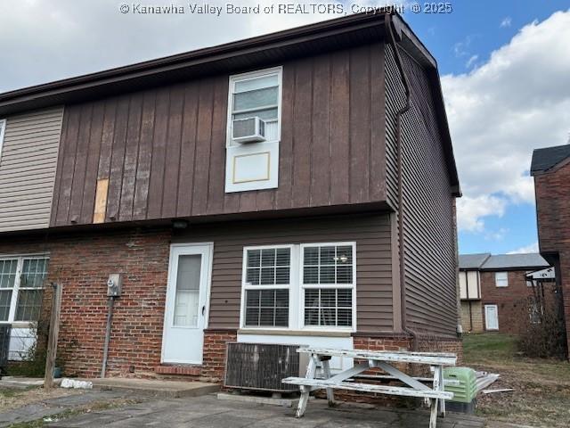 back of house with cooling unit and brick siding