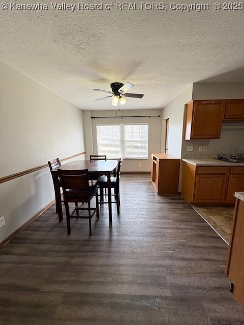 dining room featuring dark wood finished floors, a textured ceiling, baseboards, and ceiling fan