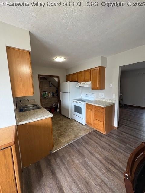 kitchen featuring dark wood-style floors, white appliances, brown cabinetry, and a sink