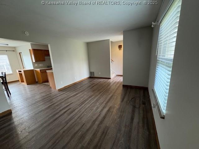 unfurnished living room featuring dark wood-style floors, visible vents, and baseboards