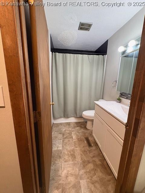 bathroom featuring a textured ceiling, toilet, a shower with shower curtain, vanity, and visible vents