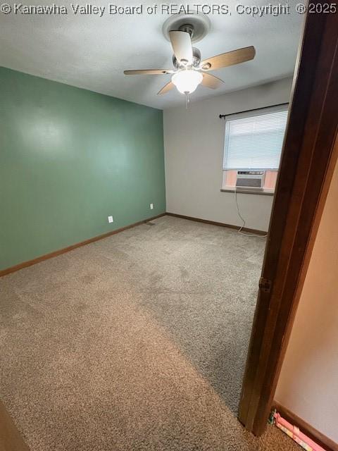 carpeted spare room featuring cooling unit, baseboards, and a ceiling fan