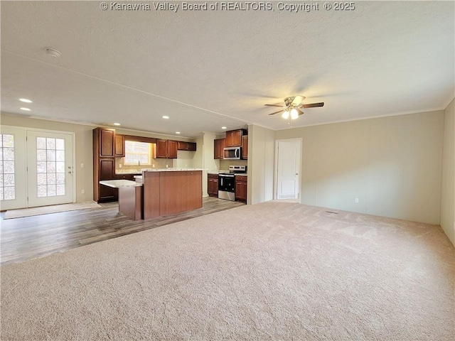 kitchen with open floor plan, stainless steel appliances, carpet, and a center island