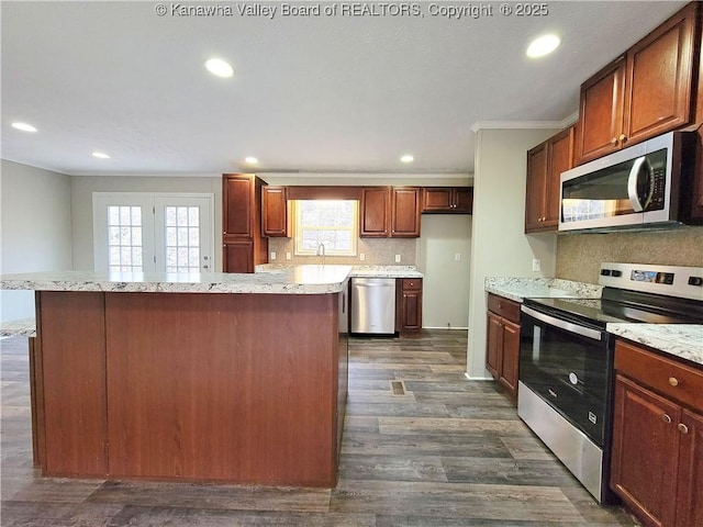 kitchen featuring a center island, stainless steel appliances, backsplash, dark wood-type flooring, and ornamental molding