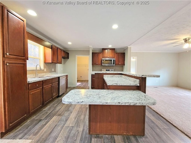 kitchen with dark wood-type flooring, appliances with stainless steel finishes, a kitchen island, and a sink