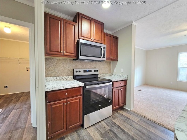 kitchen featuring stainless steel appliances, ornamental molding, wood finished floors, and decorative backsplash