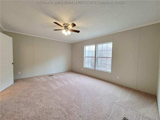 carpeted empty room featuring ornamental molding, a textured ceiling, and a ceiling fan