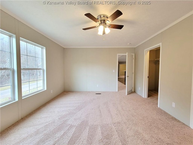 carpeted empty room with ornamental molding and a ceiling fan