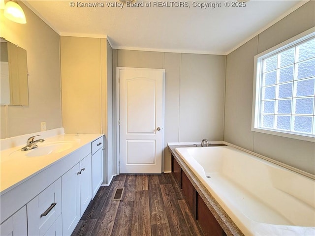 bathroom with a garden tub, visible vents, wood finished floors, and vanity