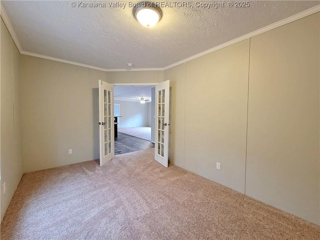 carpeted spare room with a textured ceiling, french doors, and crown molding