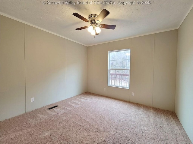 spare room with carpet, visible vents, crown molding, and a textured ceiling