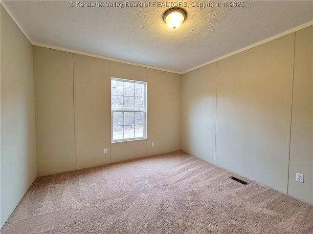 carpeted spare room featuring visible vents, crown molding, and a textured ceiling