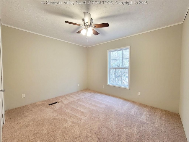 carpeted spare room with a ceiling fan, visible vents, a textured ceiling, and ornamental molding