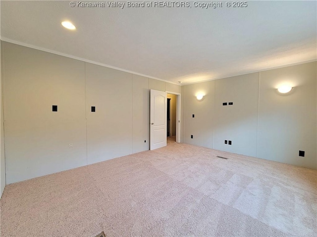 carpeted empty room with visible vents and crown molding