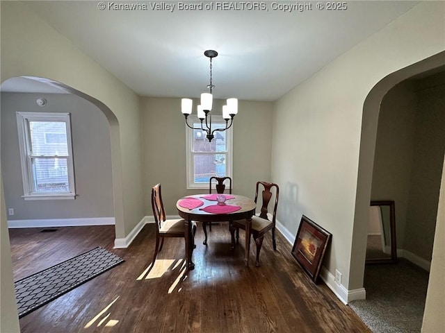 dining room featuring baseboards, plenty of natural light, arched walkways, and wood finished floors