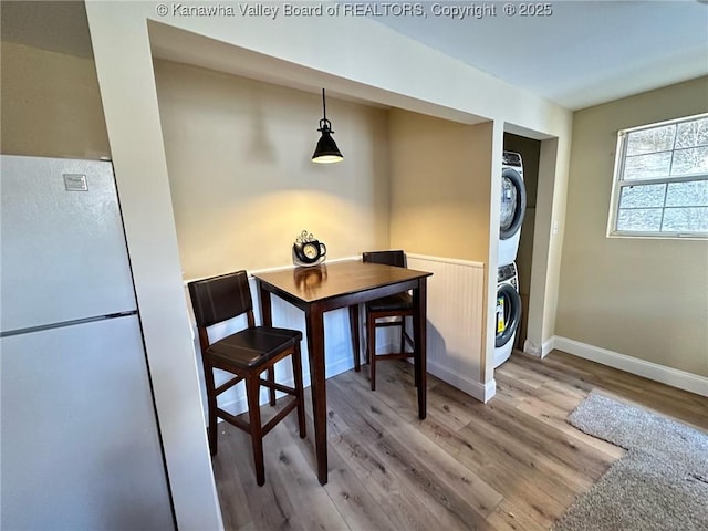 dining room featuring baseboards, wood finished floors, and stacked washer / drying machine