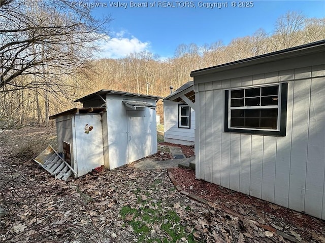 view of side of home with a storage shed and an outbuilding