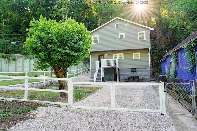 view of front of property featuring stairs, a porch, a fenced front yard, and a gate