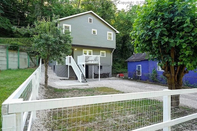 rear view of house featuring a patio, stairway, and a fenced backyard