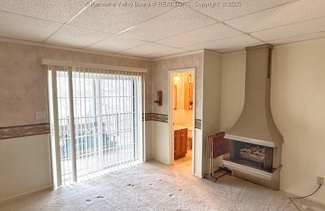 carpeted spare room featuring a drop ceiling and crown molding