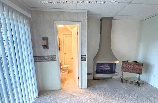 sitting room with visible vents, a paneled ceiling, carpet, and a wood stove