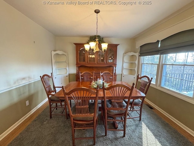 dining room with visible vents, a notable chandelier, baseboards, and wood finished floors