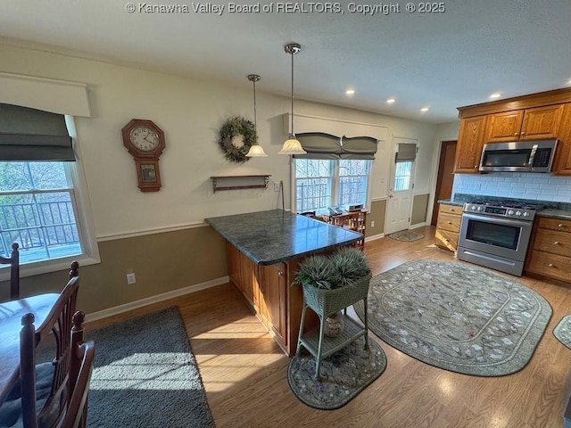 kitchen with stainless steel appliances, tasteful backsplash, brown cabinetry, and wood finished floors