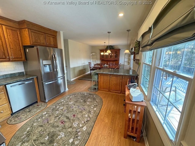 kitchen featuring brown cabinets, dark countertops, stainless steel appliances, and light wood finished floors