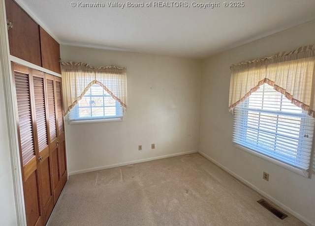 unfurnished bedroom featuring light carpet, baseboards, visible vents, and a closet