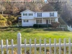 traditional-style house featuring covered porch, fence, and a front lawn