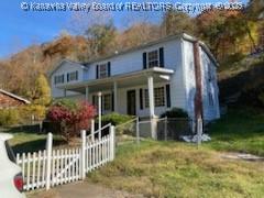 traditional home with a fenced front yard, a gate, a front lawn, and a porch