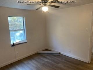 spare room with wood finished floors, a ceiling fan, and baseboards