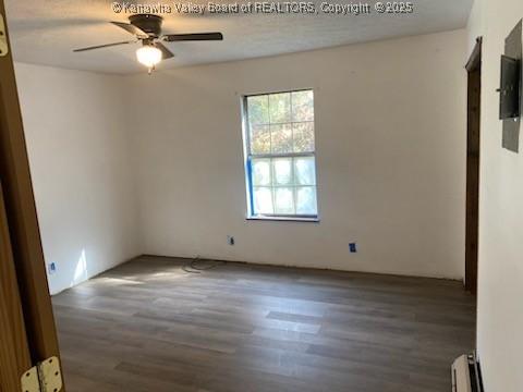 spare room featuring a baseboard radiator, wood finished floors, and a ceiling fan