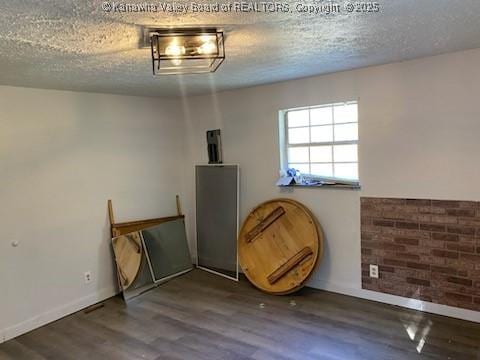 unfurnished room featuring wood finished floors, baseboards, and a textured ceiling