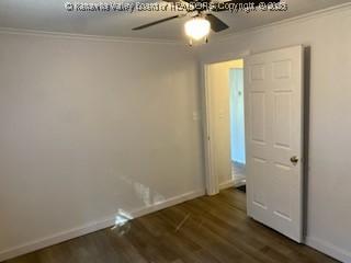 interior space with baseboards, dark wood-type flooring, ornamental molding, and a ceiling fan