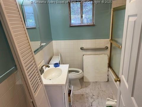 full bathroom featuring toilet, tile walls, wainscoting, and vanity