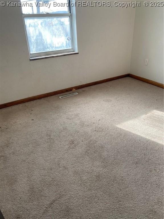 carpeted spare room featuring visible vents and baseboards