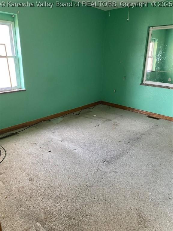 unfurnished room with carpet, visible vents, and baseboards