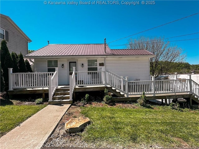 view of front of home with a deck, metal roof, and a front yard