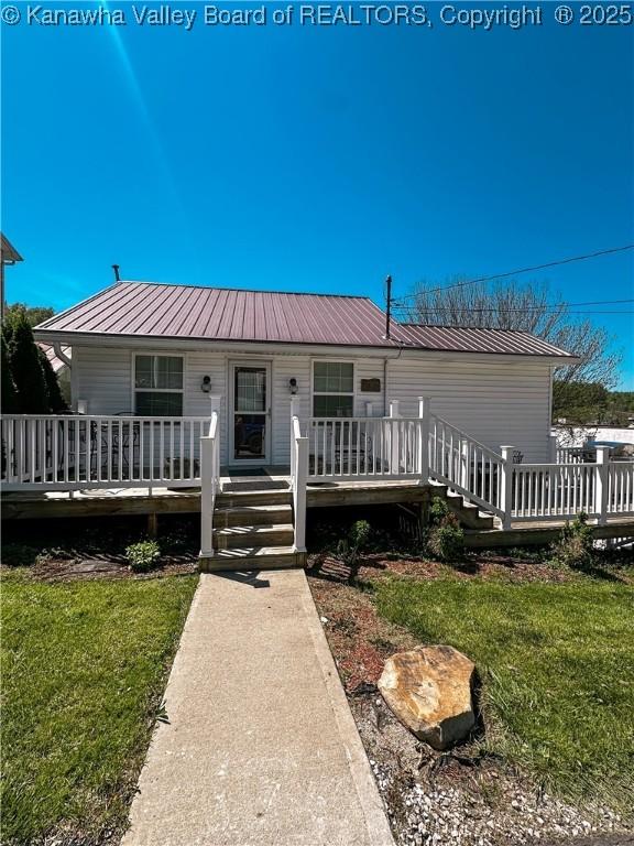 view of front of house with a front yard, metal roof, and a wooden deck